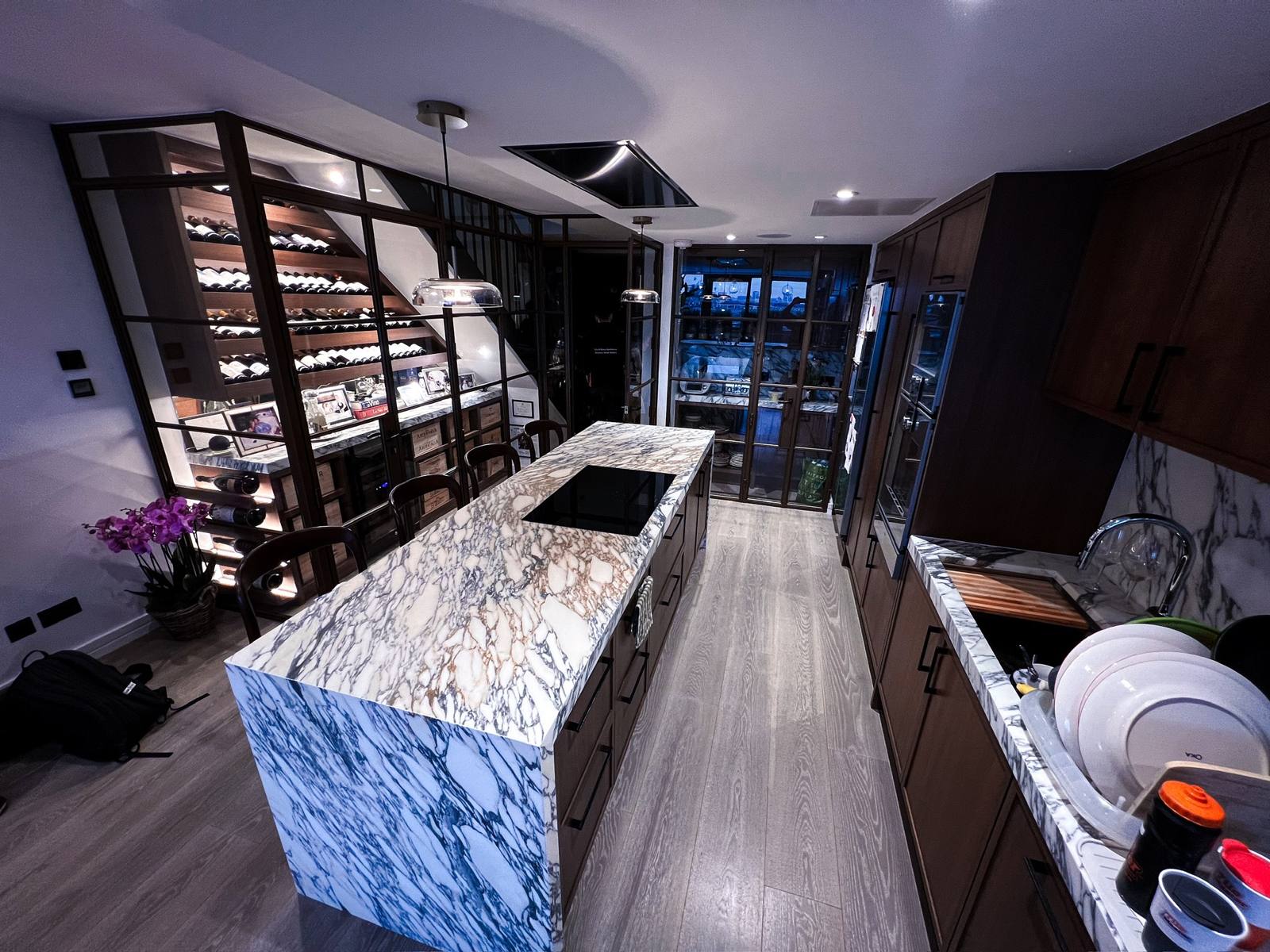 Marble kitchen island in front of a glass wine wall