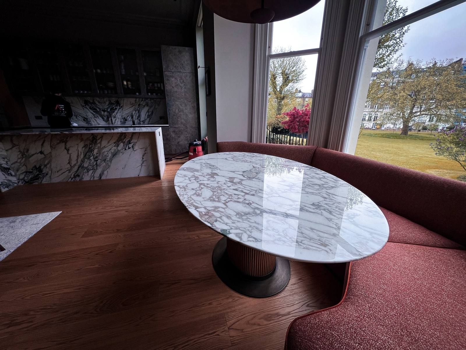 Oval marble dining table beside a curved banquette