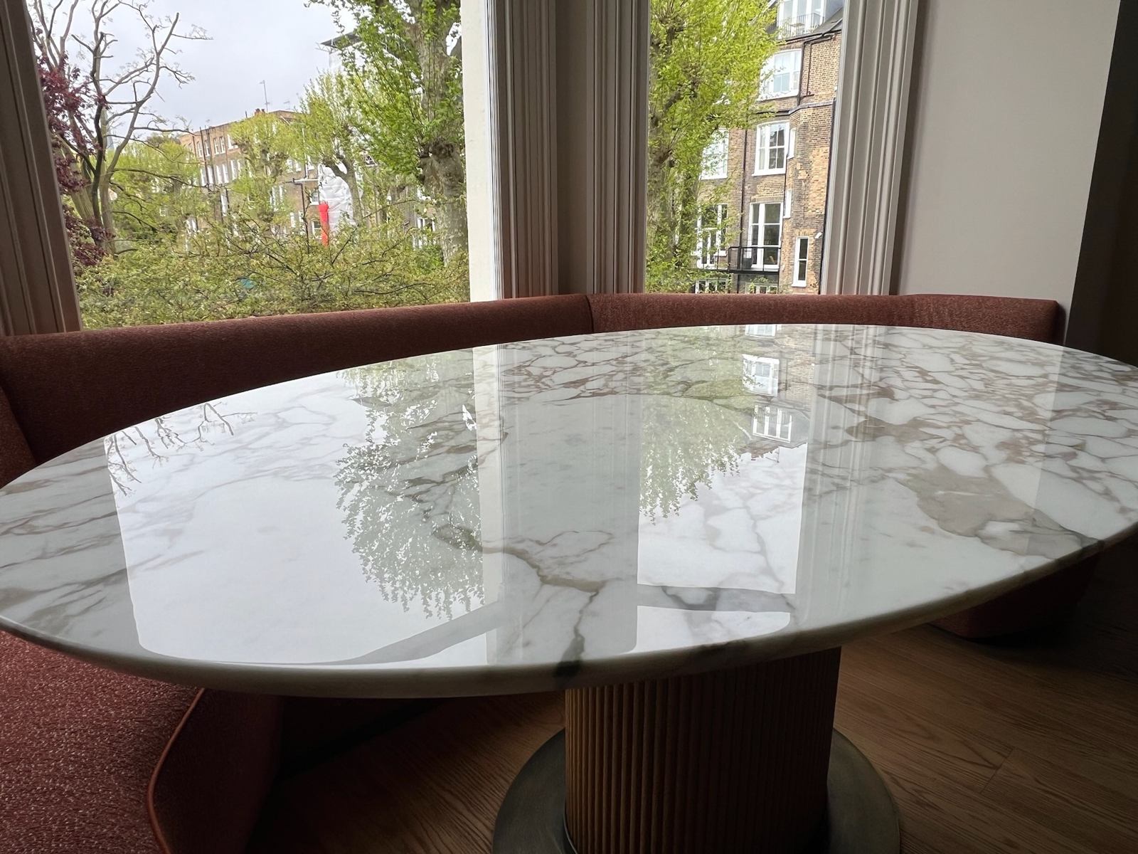 Close-up of a polished oval marble table with a garden view